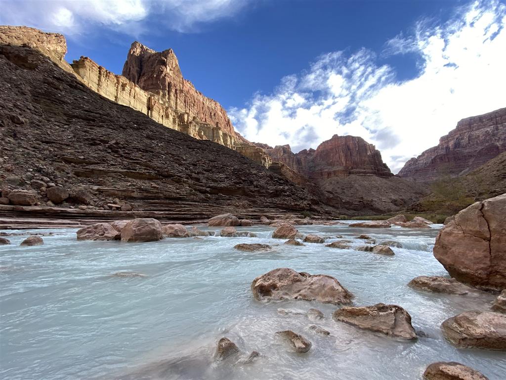 The Colorado River flowing through a desert canyon in Arizona, framed by layered sandstone cliffs
