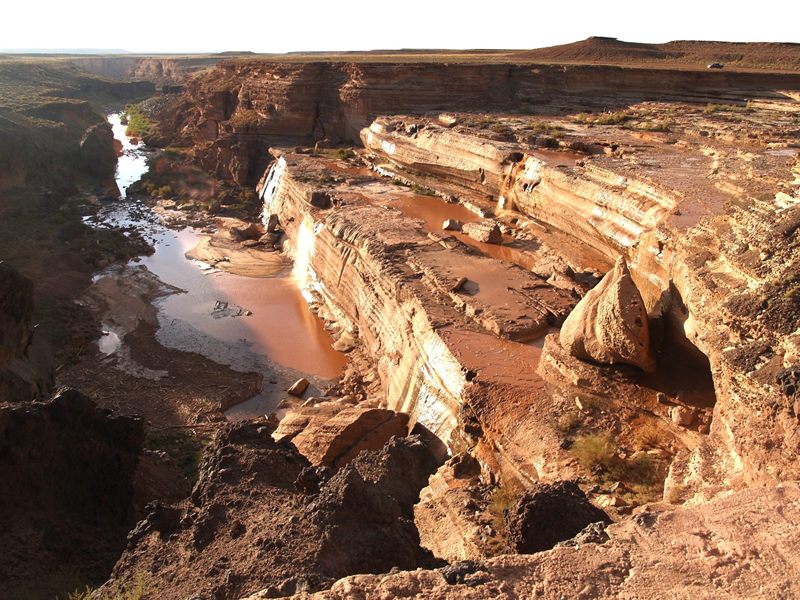 Grand Falls canyon on the Little Colorado River, Arizona, with layered sandstone cliffs and sediment-brown water pools