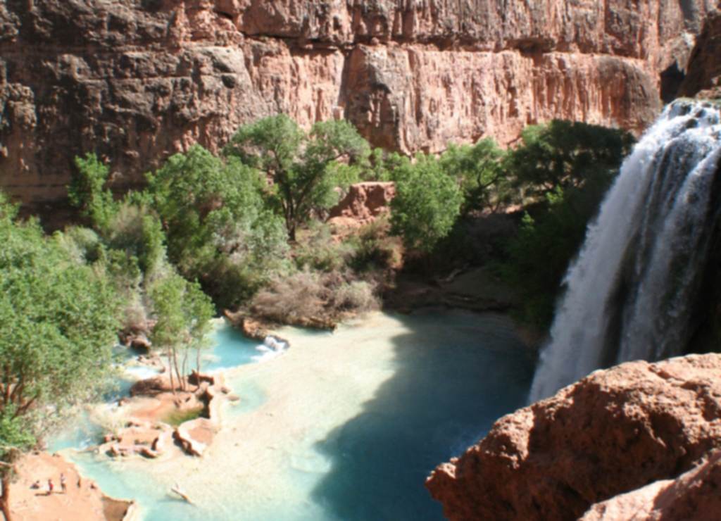 Havasu Falls pouring into its turquoise pool beneath red canyon walls on the Havasupai reservation in the Grand Canyon