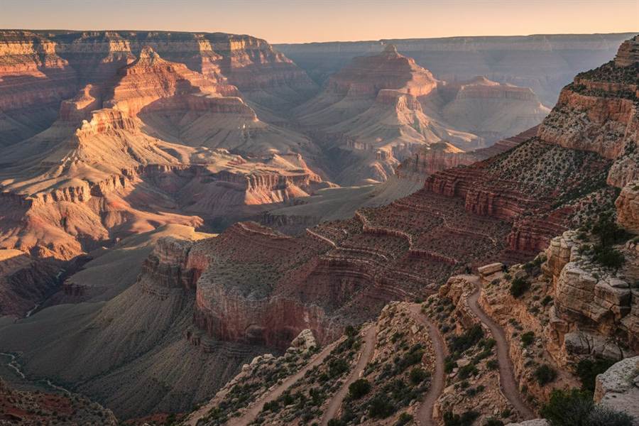 Hikers on a switchback trail below the South Rim of the Grand Canyon at golden hour